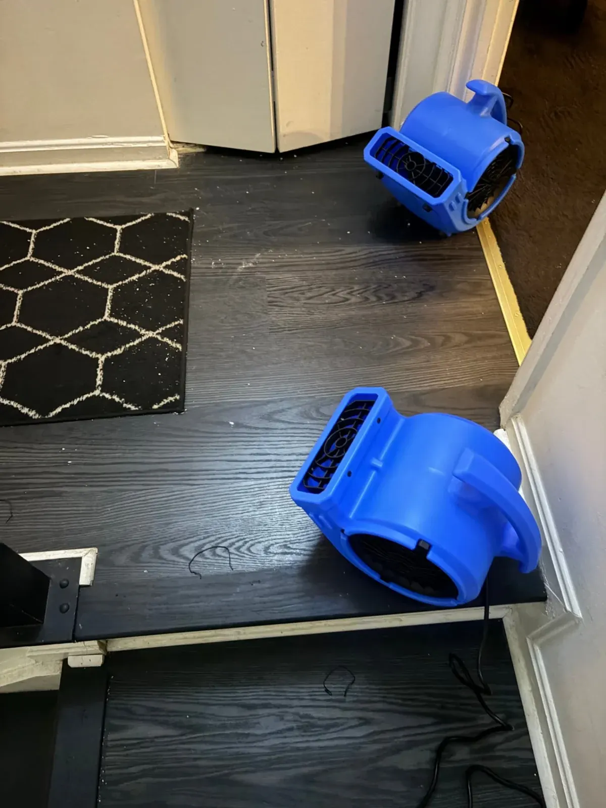 Two blue air movers positioned on a kitchen floor during EMC water damage drying