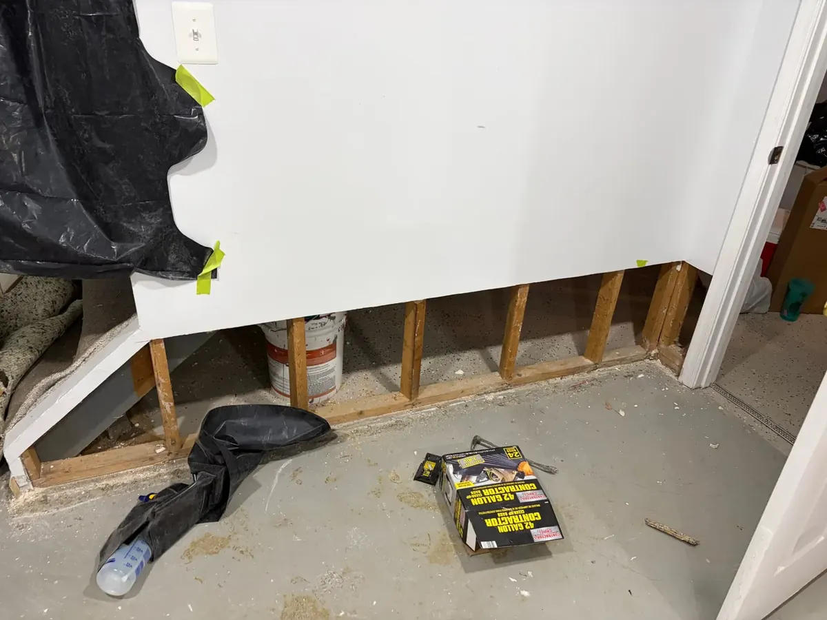 Flood cut along the bottom of a basement wall with wet drywall removed to the studs on an EMC water damage project