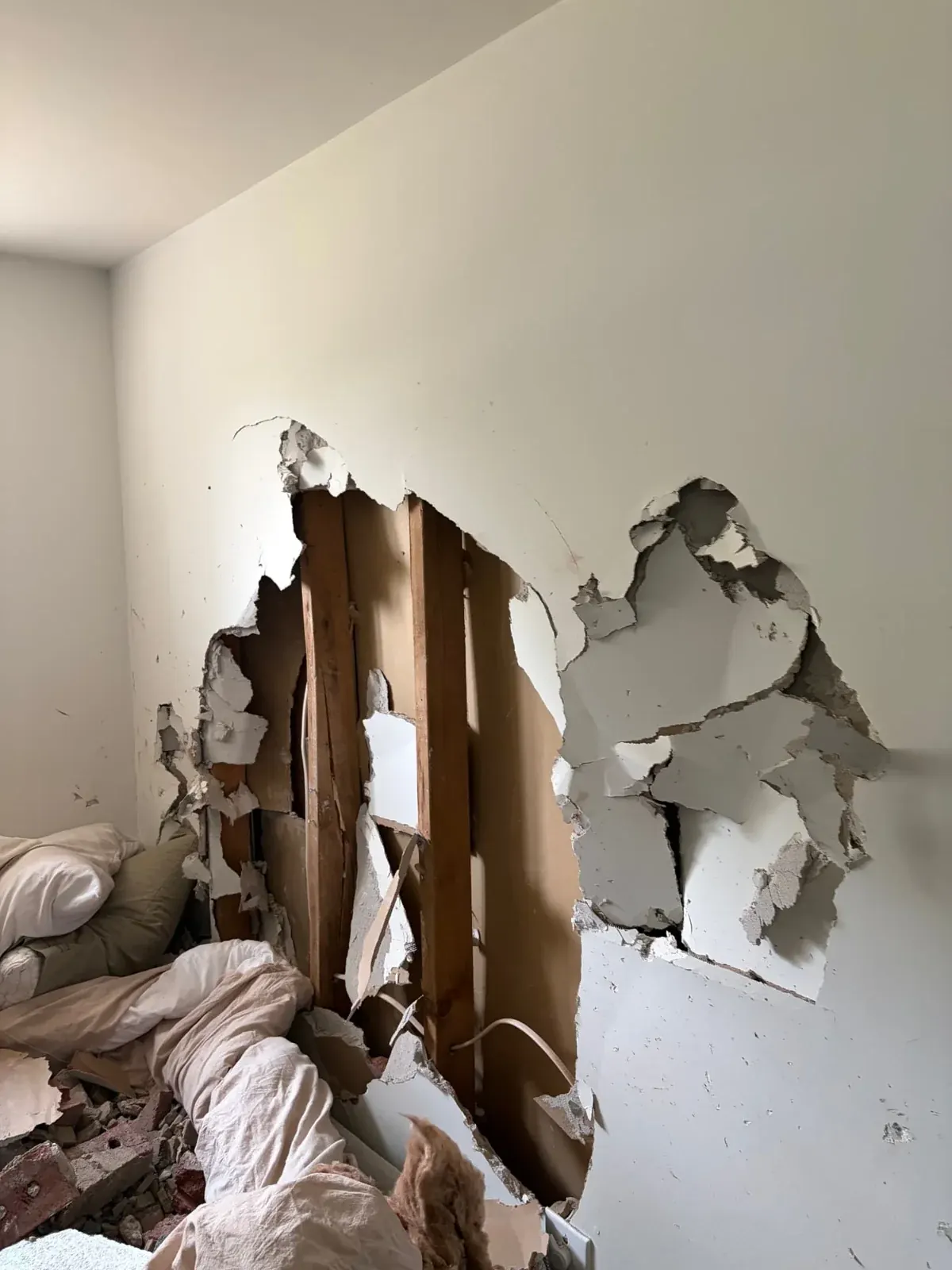 Broken drywall and exposed framing inside a home following vehicle impact damage